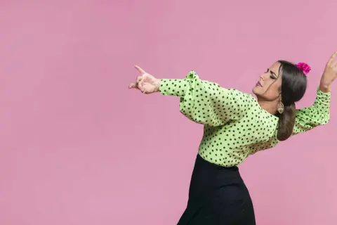 Mujer con blusa verde de lunares y falda negra, lista para bailar sevillanas con gracia y pasión.