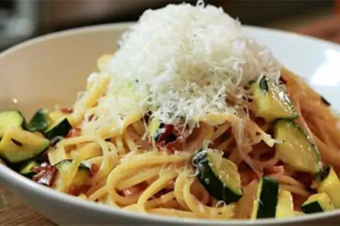 Spaghetti mit Zucchini und Speck, gekrönt mit frisch geriebenem Parmesan. Eine köstliche Zucchini Carbonara.
