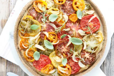 Tarte tomate claire au matcha, garnie de tomates multicolores, oignons, ail, romarin et basilic frais. Une œuvre culinaire colorée et savoureuse.