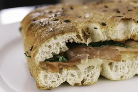 Un sandwich gourmand garni de jambon et de fromage, servi dans un pain italien moelleux et croustillant.