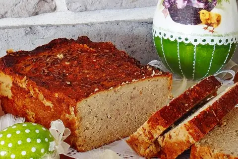Pyszny pasztet drobiowo-wieprzowy z wątróbką, idealny na wielkanocny stół, obok ozdobnych jajek.