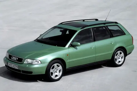 Zielony kombi Audi A4 B5 z relingami dachowymi i szyberdachem, zaparkowany na betonowej nawierzchni.