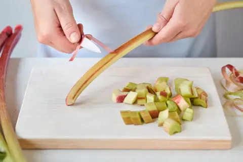 Hände schälen Rhabarber für herzhafte rhabarber rezepte hauptgerichte. Gekochter Rhabarber passt gut zu Fleisch.