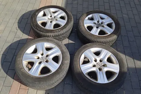Cztery felgi strukturalne Opel z oponami leżą na chodniku.