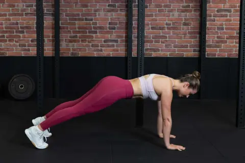 Frau in einem Fitnessstudio macht eine Plank-Übung für ihr **core training**.