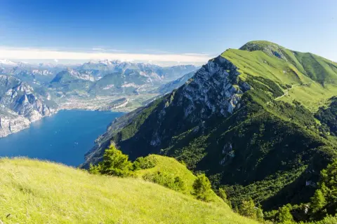 Panoramica mozzafiato dal Monte Baldo: lago blu intenso, montagne verdi e un cielo limpido.