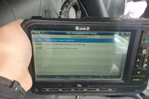 Escáner G-SCAN 2 muestra código C1201, fallo en sistema de control de motor de un Toyota.