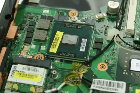 Nahaufnahme eines geöffneten Laptops, bereit für den **laptop cpu wechseln**. Der Prozessor ist sichtbar, umgeben von grüner Platine und Kabeln.