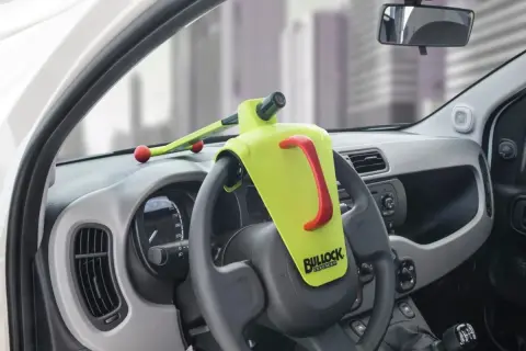 Un antivol de volant Bullock Defender est installé. Il est jaune vif avec une poignée rouge. Il n'y a pas de clé visible, ce qui peut faire penser à comment débloquer un volant sans clé.