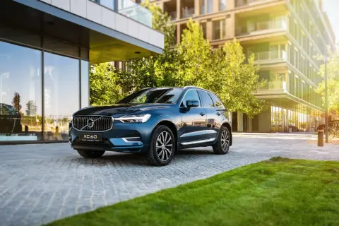 Elegancki, ciemnoniebieski Volvo XC60 zaparkowany przed nowoczesnym budynkiem. Wiele osób szuka volvo xc60 opinie, by podjąć decyzję o zakupie.