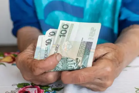 Dłonie trzymają polskie banknoty 100 zł i 10 zł. Pytanie: umowa zlecenie - ile na godzinę netto?