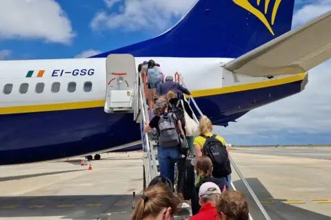 Pasażerowie wchodzą po schodkach do samolotu Ryanair. Czy to opłata transakcyjna Ryanair?