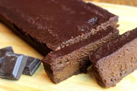 Un délicieux gâteau chocolat compote, coupé en tranches, avec des carrés de chocolat à côté.