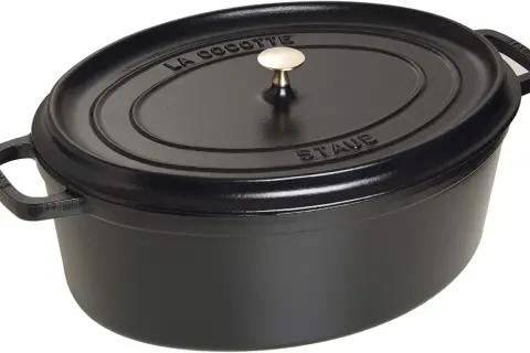 Schwarzer ovaler Schmortopf von Staub mit goldfarbenem Griff. Perfekt für langsam gegarte Gerichte, was ein Schmortopf eben ist.