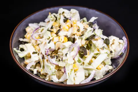 Frischer Chinakohl Salat mit Mais, roten Zwiebeln und Kürbiskernen in cremiger Soße.