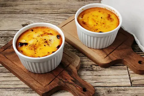 Zwei Portionen Crema Catalana Eis, karamellisiert und auf Holzbrettern serviert.