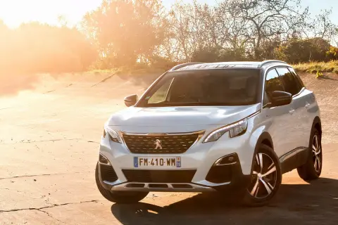 Blanco Peugeot 3008 Hybrid4 aparcado en un camino de tierra al atardecer.
