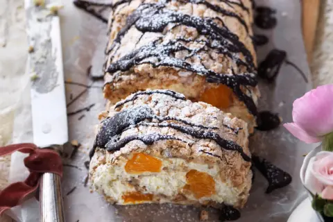 En läcker budapestbakelse med vispgrädde, frukt och chokladdrizzle, pudrad med florsocker.