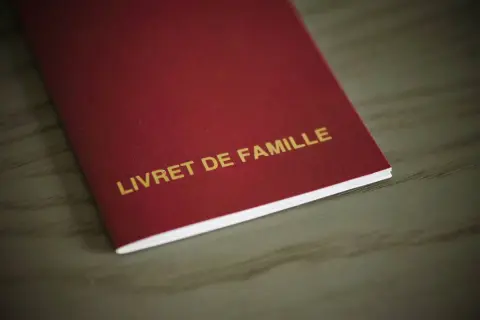 Livre rouge "LIVRET DE FAMILLE" avec mention marginale, document officiel de famille.