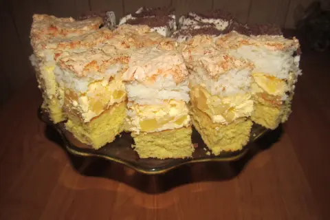 Pyszne ciasto z ananasem i kokosem, z bezą i kremem, pokrojone na kawałki na paterze.