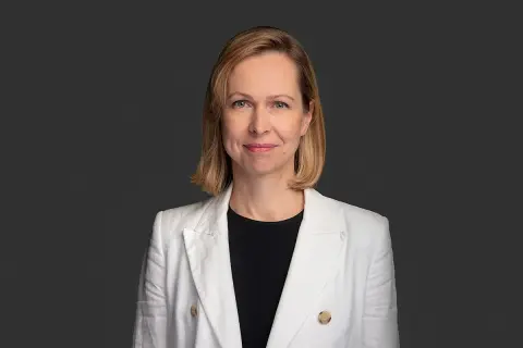 Uśmiechnięta kobieta w białej marynarce, profesjonalny terapeuta autyzmu, gotowa do pomocy.