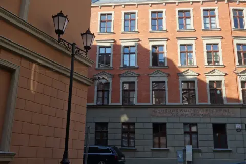 Urokliwe kamienice Gdańska z latarniami ulicznymi i ceglaną fasadą.