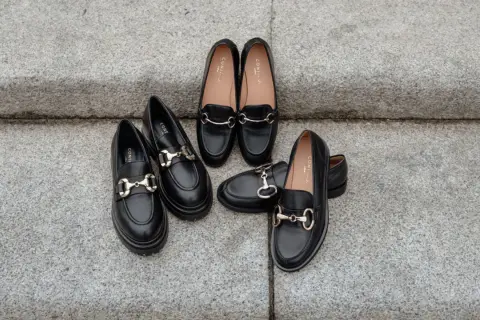 Scarpe nere eleganti con morsetto dorato, perfette come scarpe per vestito corto.
