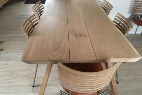 Ett modernt ekbord med en naturlig, pigmenterad oljeyta, omgivet av stilrena stolar med träribbor och lädersits.