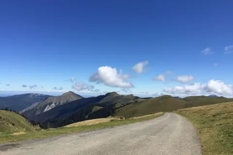 Route sinueuse menant au port de Bales, traversant des paysages de montagnes verdoyantes sous un ciel bleu éclatant.