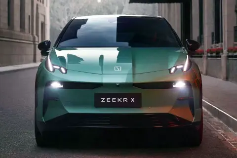 El elegante Zeekr X verde se detiene en una calle urbana, sus luces LED brillan intensamente.