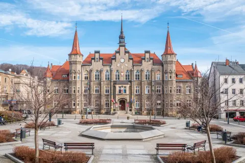 Ratusz w Wałbrzychu, serce wałbrzych stare miasto, z wieżyczkami i zegarem. Plac z fontanną i ławkami.