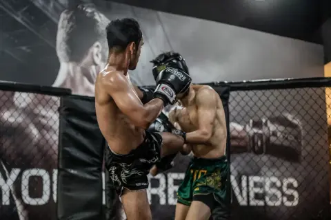 Two fighters in a ring. One lands a kick, likely feeling what does it feel like to get hit in the liver.