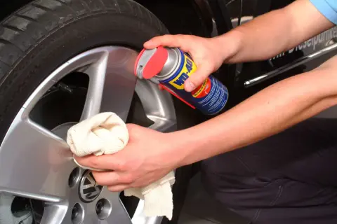Hände reinigen Felgen mit WD-40 und Tuch. Ein einfacher felgenreiniger hausmittel-Trick für glänzende Alufelgen.