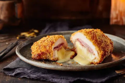 Un cordon bleu coupé en deux, révélant un fromage fondant et du jambon. Le secret d'un bon quel fromage pour cordon bleu réside dans sa texture crémeuse.
