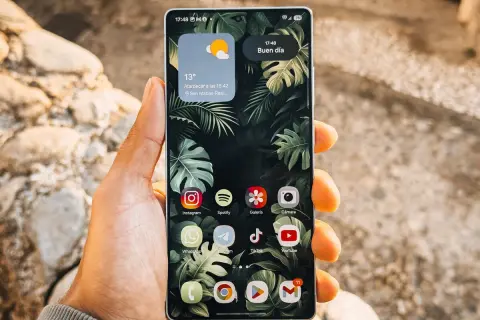 Mano sujetando un teléfono Android con iconos de aplicaciones personalizables, mostrando cómo cambiar tamaño iconos android para una mejor visualización.