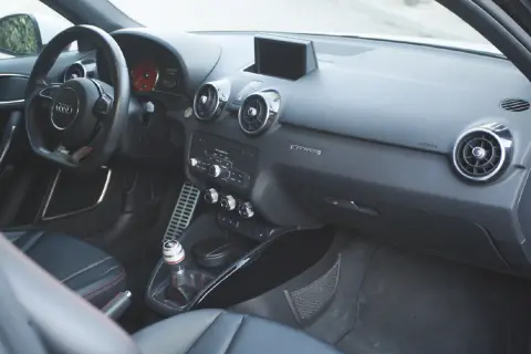 Vue de l'intérieur d'une Audi A1, avec le volant, la console centrale et les sièges en cuir noir.