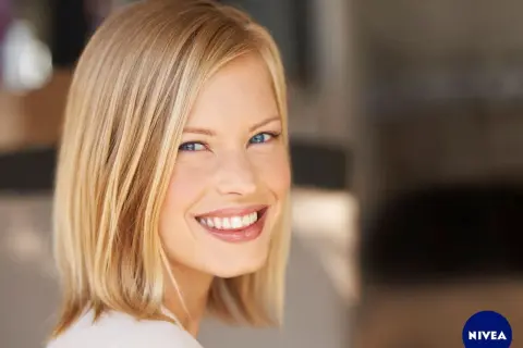 Lächelnde Frau mit blondem Bob, ein moderner **haarschnitt frauen**. Ihr Blick ist strahlend, die Haut makellos.