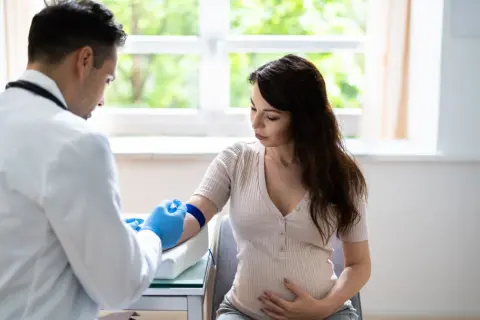Lekarz pobiera krew od ciężarnej kobiety, badając podwyższone neutrofile w ciąży.