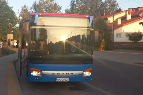 Niebieski autobus Setra z Giżycka do Olsztyna, sprawdzam express bus Giżycko Olsztyn cena. Słońce odbija się w szybie.