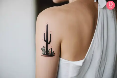 Delikatny kaktus tatuaz na ramieniu, otoczony pustynnymi roślinkami.