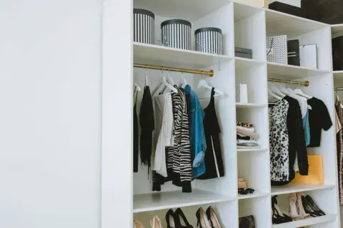 Estanterías armario con ropa colgada, cajas y zapatos organizados.