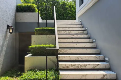 Moderne idee scale esterne in muratura con gradini in marmo e aiuole verdi.
