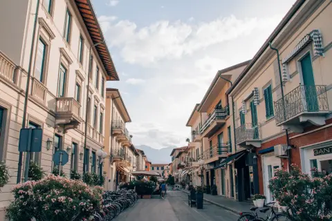 Strada pittoresca a Forte dei Marmi, Italia, con palazzi color pastello, balconi in ferro battuto e biciclette parcheggiate.