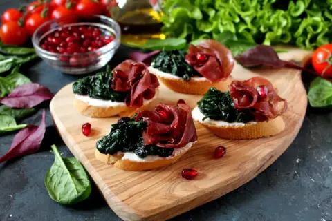 Leckere Bruschetta mit Spinat, Schinken und Granatapfelkernen – eine tolle Kombination eisenhaltiger Lebensmittel.