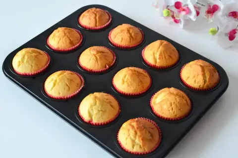 Upieczone, wilgotne muffinki jogurtowe w czerwonych papilotkach, gotowe do jedzenia.
