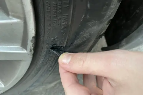 Un pneu abîmé sur le flanc, probablement suite à un choc contre le trottoir. La gomme est déchirée.