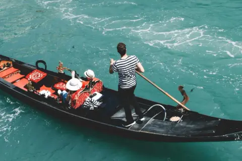Gondola w Wenecji z pasażerami i gondolierem. Zastanawiasz się, ile kosztuje gondola w Wenecji?