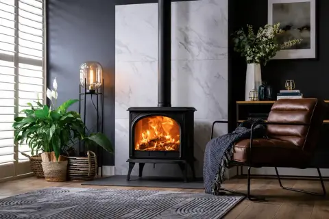 Poêle à bois en fonte, cœur de la pièce, réchauffant l'atmosphère. Un fauteuil en cuir invite à la détente.
