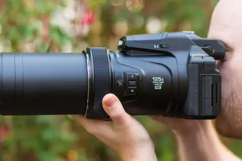 Un uomo usa una fotocamera bridge con zoom 125x. Scopri cosa sono le fotocamere bridge e la loro versatilità.