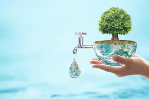Dłoń trzyma planetę Ziemię z drzewem, z której kapie kropla wody. Kurek symbolizuje, jak oszczędzać wodę w domu.